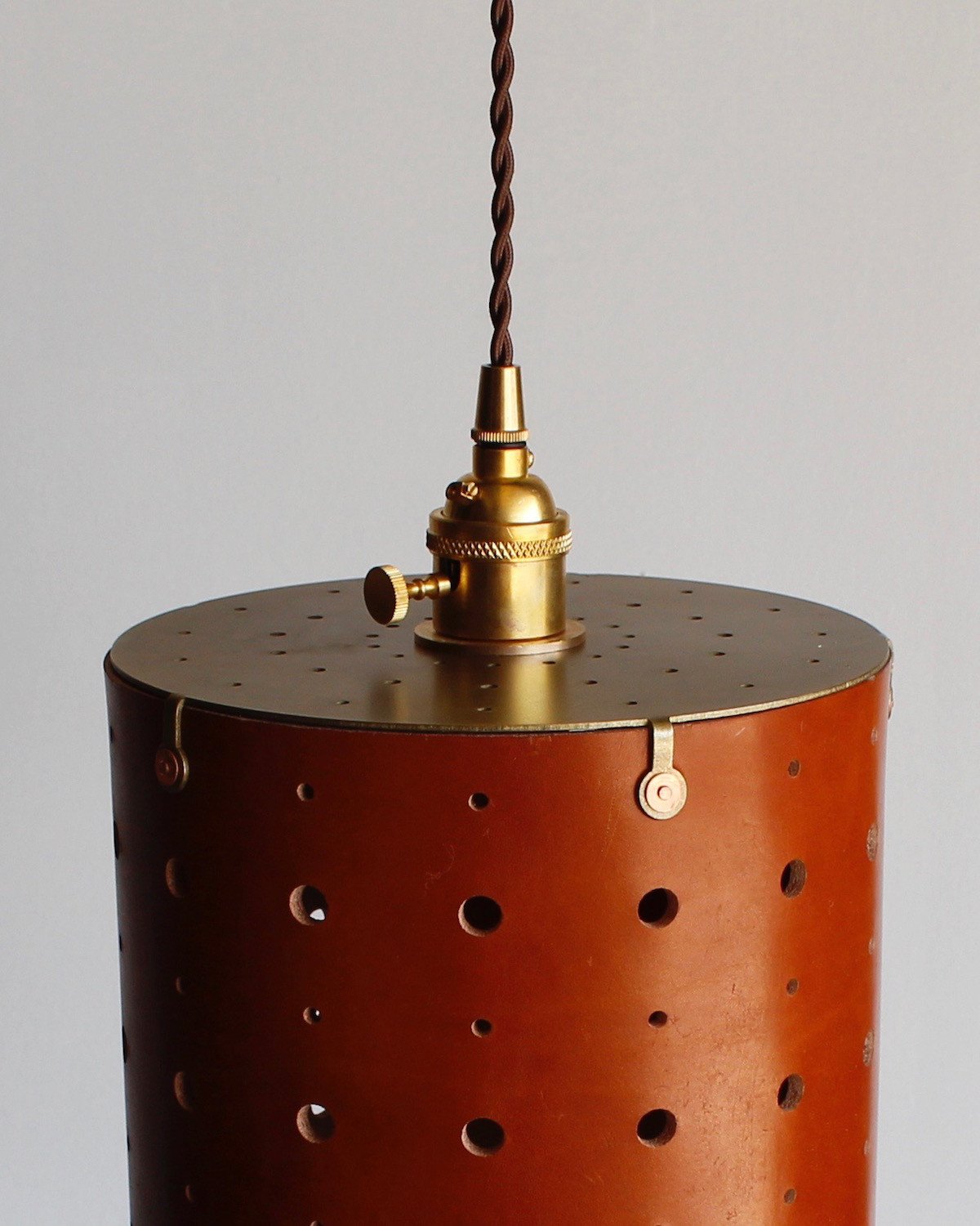 Tan leather cylinder pendant with handstitched, perforated leather shade. Made by Lostine in Philadelphia. Hardwired or plug light fixture. Simple interior design, made in the USA. #color_tan harness