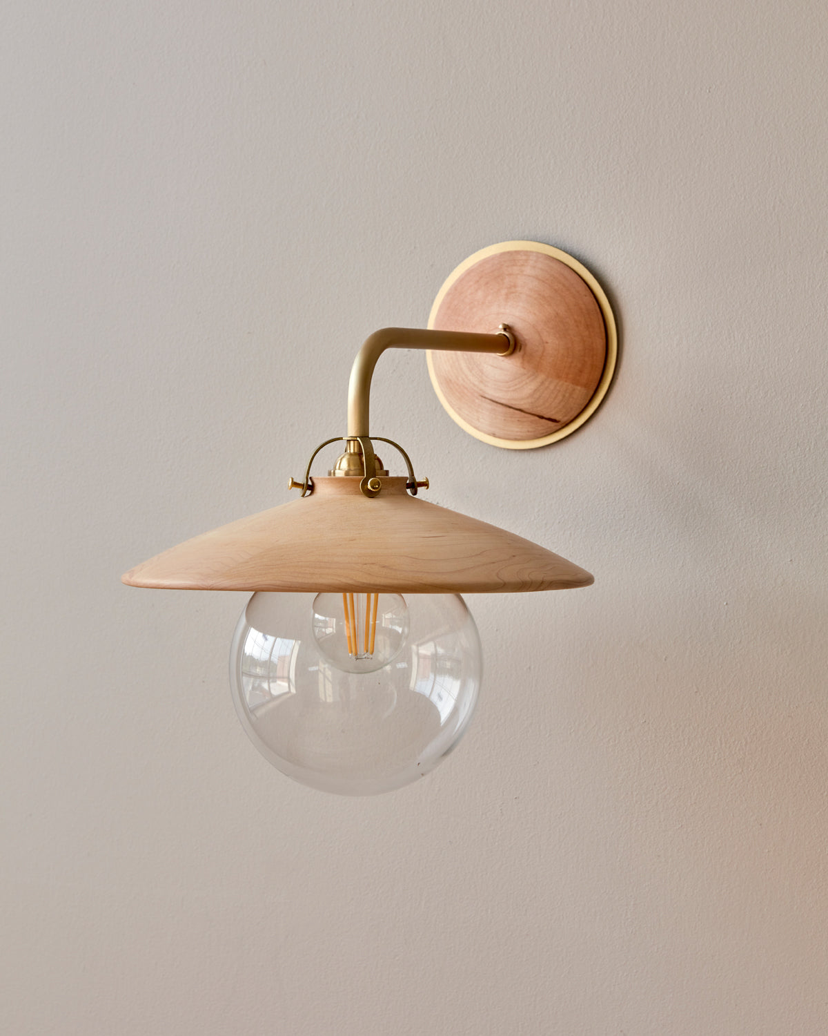 Hardwired satin brass wall sconce with decorative wooden natural maple shade and glass globe