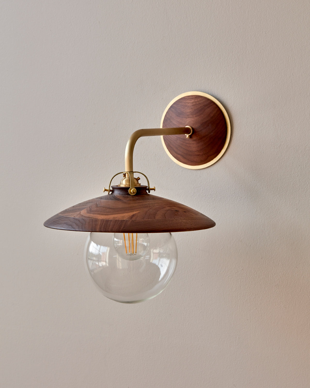 Hardwired satin brass wall sconce with decorative wooden black walnut shade and glass globe