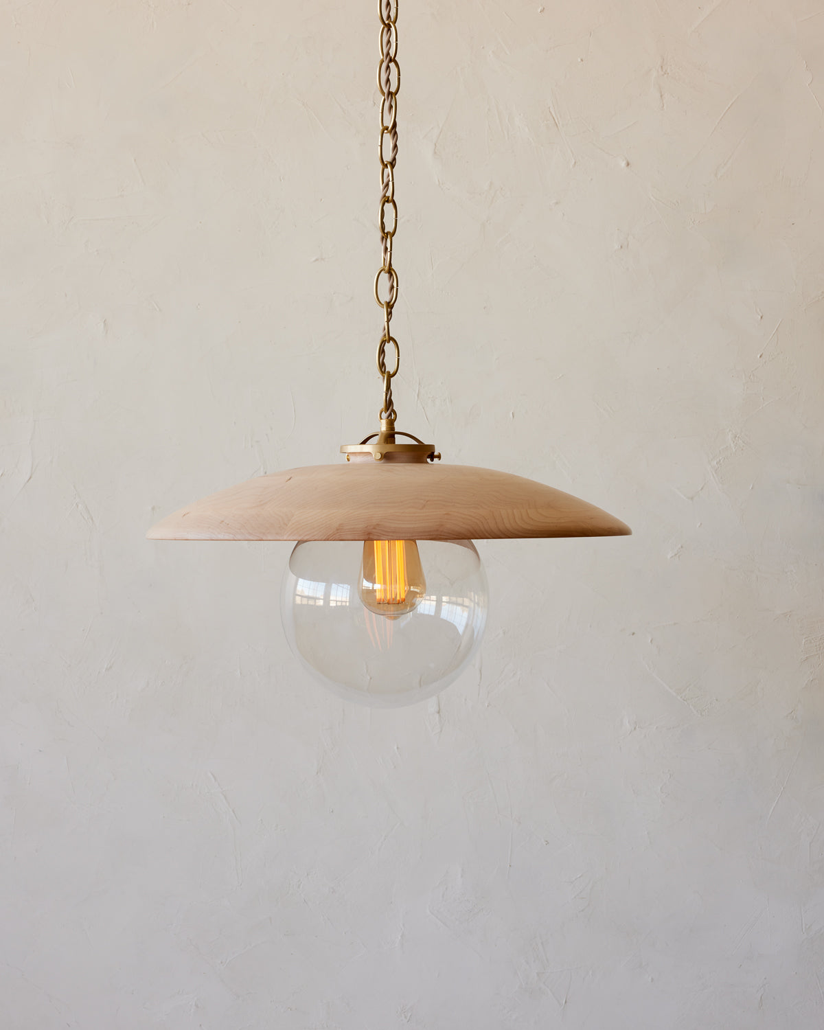 Large pendant light with oversized clear glass globe and decorative wooden clear maple shade with brass chain