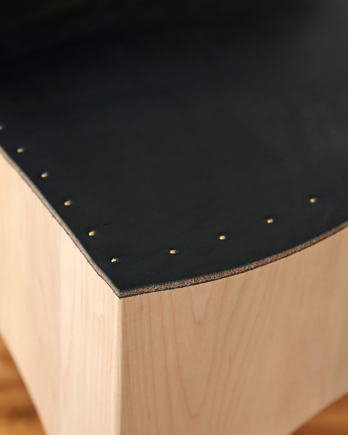 Brass nails of Sculpted stool with black leather and maple wooden base with metal foot rest and short backrest. Counter and bar height. Handmade in Philadelphia by Lostine. Simple Interior Design. Warm American Modern Design