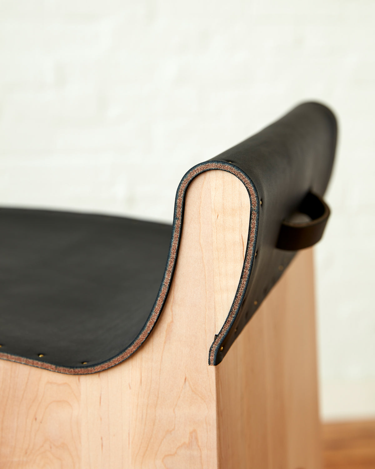 Sculpted stool with black leather and maple wooden base with metal foot rest and short backrest. Counter and bar height. Handmade in Philadelphia by Lostine. Simple Interior Design. Warm American Modern Design