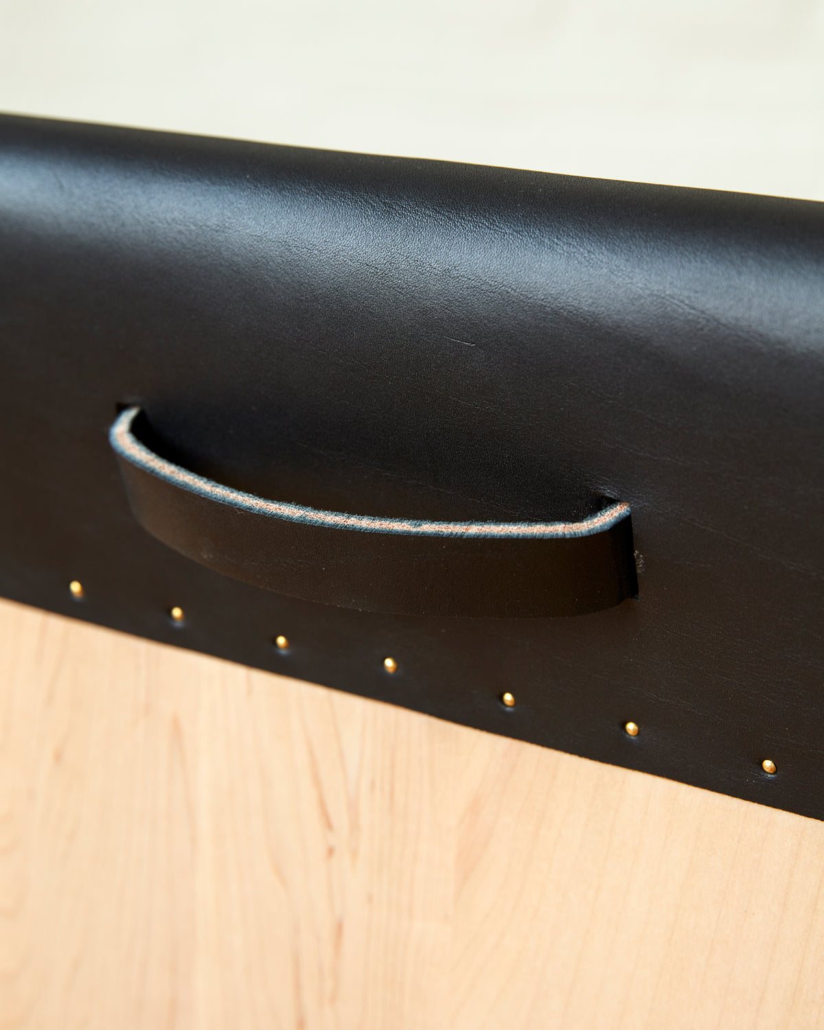 Leather pull handle of Sculpted stool with black leather and maple wooden base with metal foot rest and short backrest. Counter and bar height. Handmade in Philadelphia by Lostine. Simple Interior Design. Warm American Modern Design