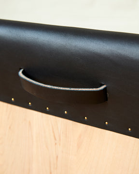 Leather pull handle of Sculpted stool with black leather and maple wooden base with metal foot rest and short backrest. Counter and bar height. Handmade in Philadelphia by Lostine. Simple Interior Design. Warm American Modern Design