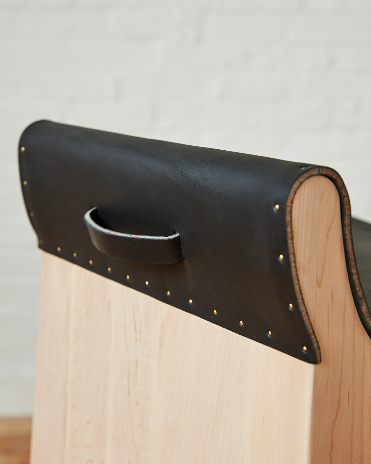 Leather pull handle of Sculpted stool with black leather and maple wooden base with metal foot rest and short backrest. Counter and bar height. Handmade in Philadelphia by Lostine. Simple Interior Design. Warm American Modern Design