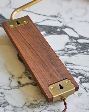 Black walnut wooden wall sconce with articulating brass arm and tan leather