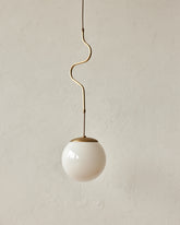 Modern brass globe pendant light with warm satin brass curved body and white milk glass globe #color_satin brass