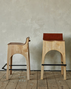 Sculpted stool with tan leather and maple wooden base with metal foot rest and short backrest. Counter and bar height. Handmade in Philadelphia by Lostine. Simple Interior Design. Warm American Modern Design